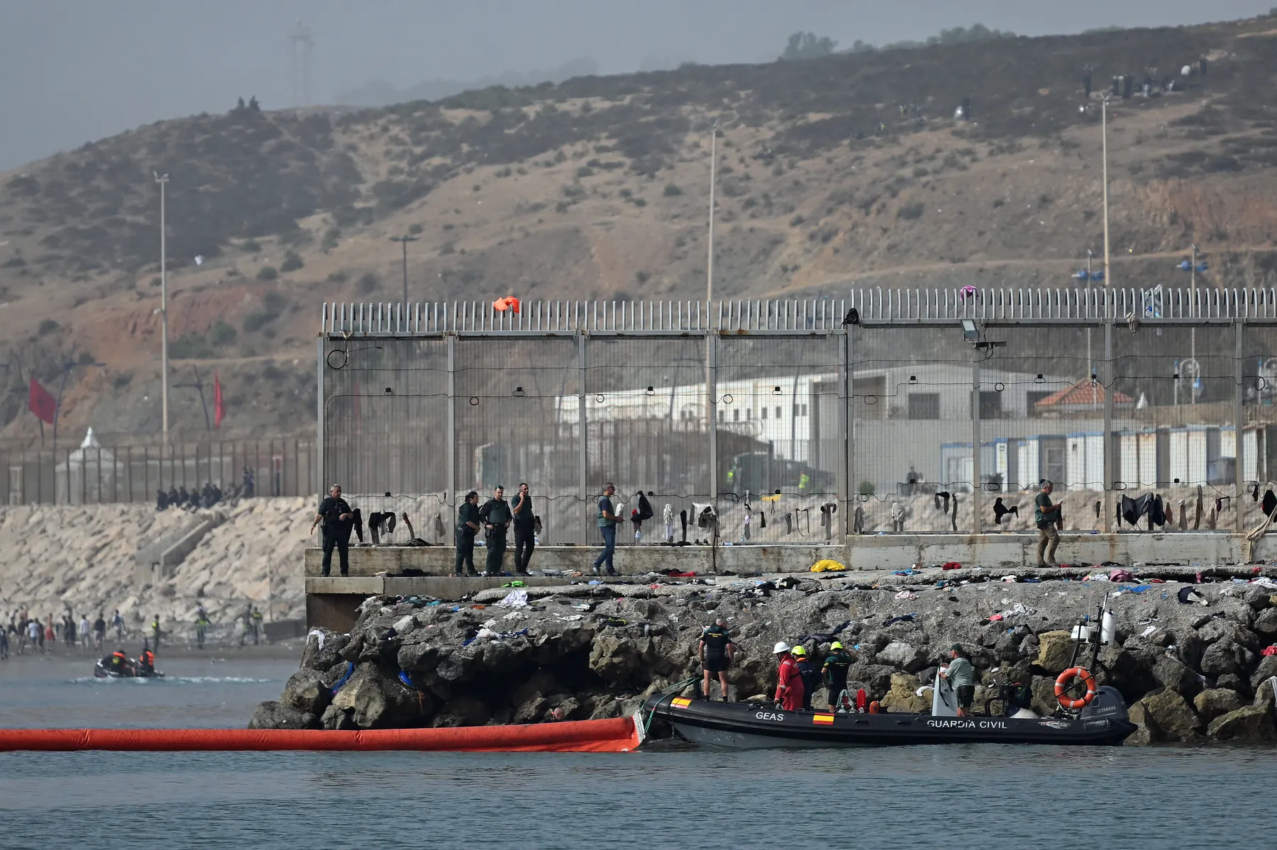 La Guardia Civil despliega una barrera naranja de contención en el espigón del Tarajal, con agentes y efectivos del GEAS junto a la valla fronteriza