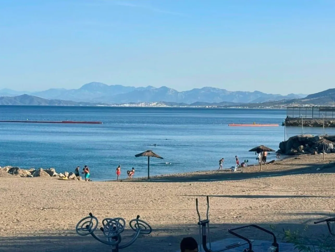 Playa de Ceuta con la barrera naranja de contención flotando en el agua